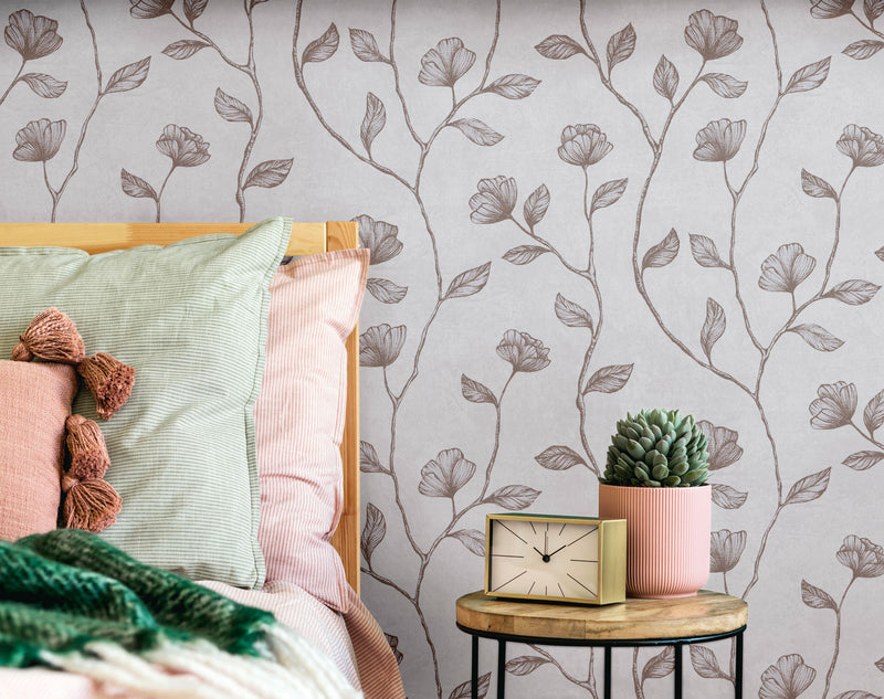 Particolare di testata letto con carta da parati botanica Europarati Friends, cuscini verde salvia e rosa cipria su comodino in legno naturale