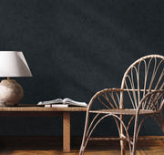 Parete antracite effetto intonaco Europarati collezione Friends con sedia in vimini e lampada da tavolo, stile minimal moderno