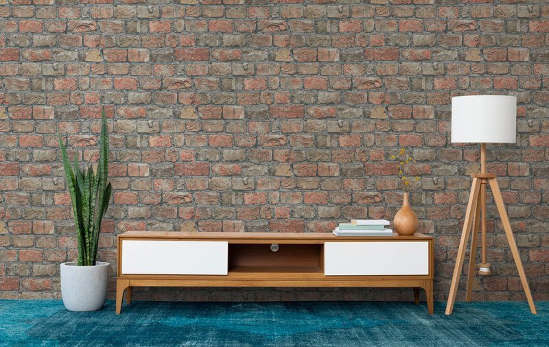 Parete decorata con carta da parati a mattoni rossi e grigi in un soggiorno moderno con mobile TV in legno, tappeto blu petrolio e lampada da terra a treppiede