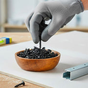 Mano con guanto da lavoro in lattice / nitrile che preleva viti per cartongesso nere fosfatate