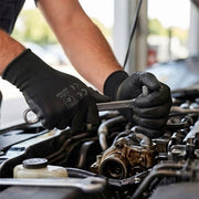 Meccanico che indossa guanti in nitrile e nylon durante la manutenzione sul motore di un auto