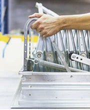 Close-up di una mano che aziona la scala retrattile, mostrando la facilità di apertura e il dettaglio della molla di tensionamento del meccanismo a scomparsa