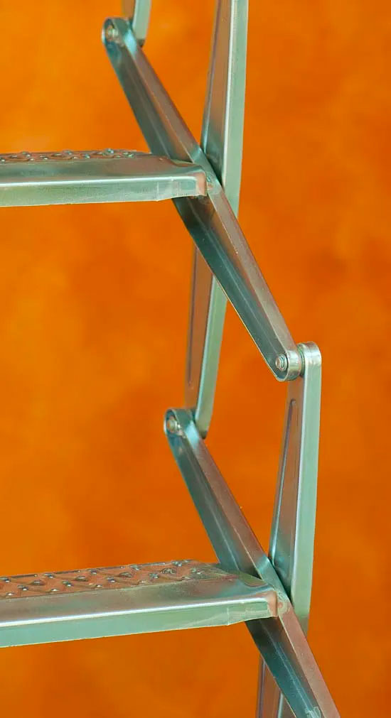 Primo piano dei gradini in metallo della scala Starlux. Il dettaglio evidenzia la sagomatura antiscivolo della pedata e i giunti a pantografo robusti