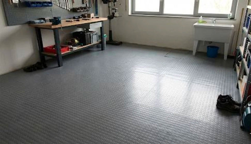 Pavimento in gomma a bolli installato in un'officina domestica con banco da lavoro e scaffalature